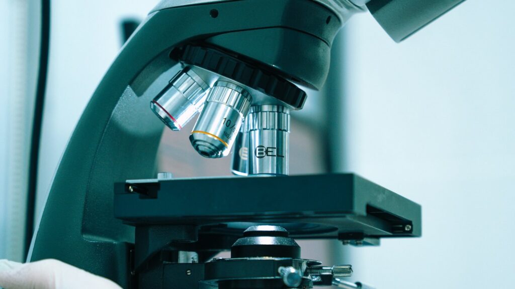 Laborant w rękawicach ustawia próbkę pod mikroskopem w laboratorium