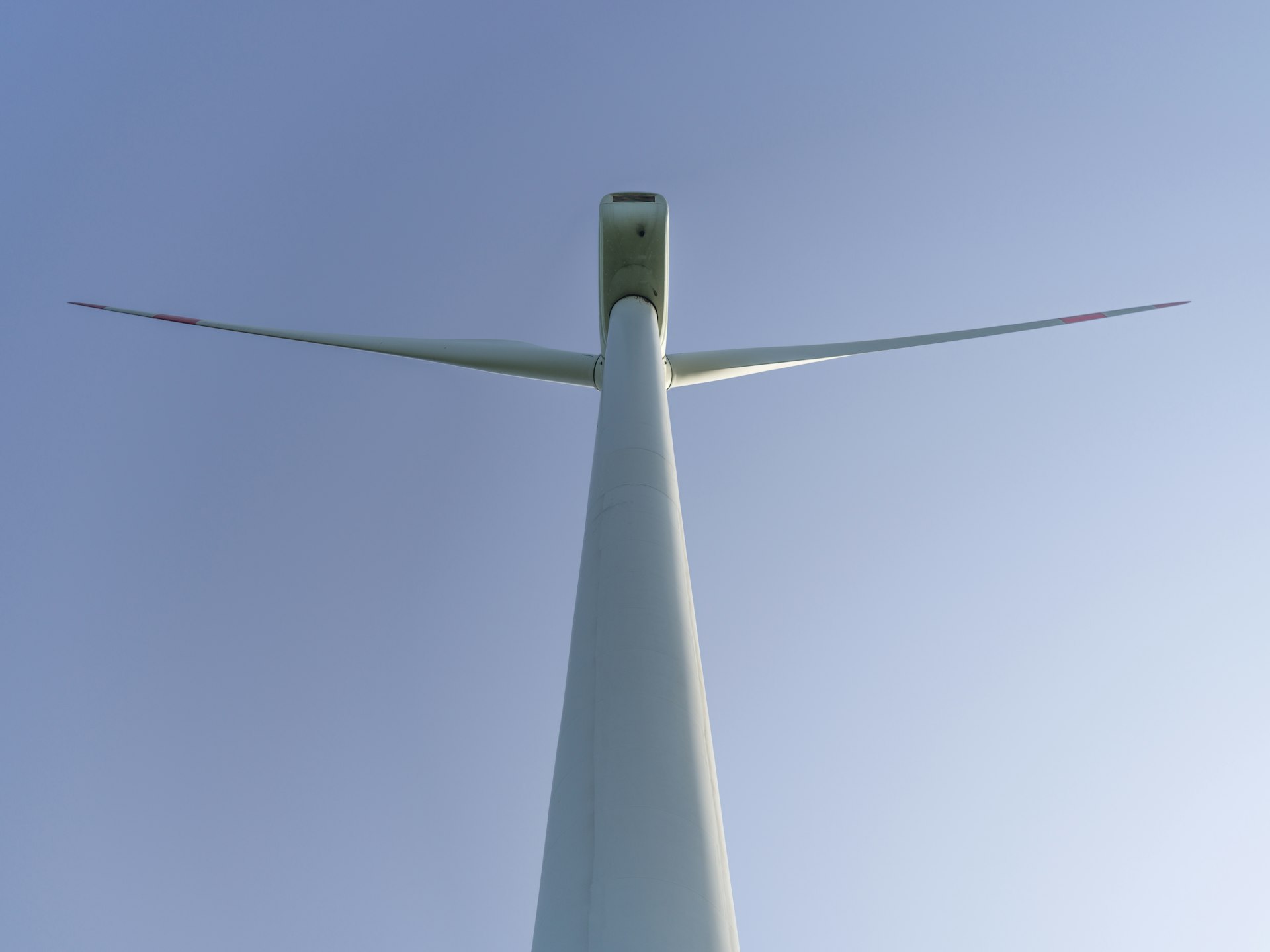 Stalowa wieża turbiny wiatrowej widziana od podstawy